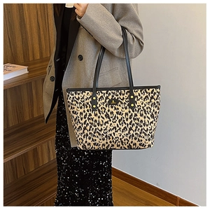 Close-up of leopard print tote bag with black leather handles and gold metal logo detail