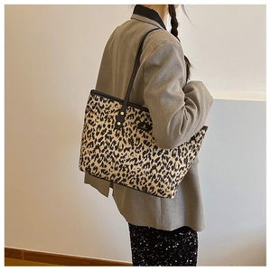 Detailed side view of large leopard print tote bag with black leather straps and studs