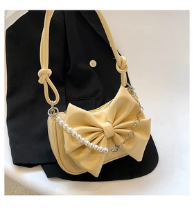 Detail view of cream shoulder bag with large bow, pearl chain and knotted strap