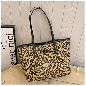 Close-up of leopard print tote bag featuring black leather handles and gold rivet details