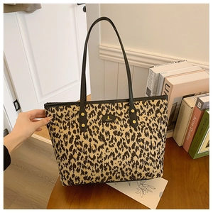 Detail of leopard print tote bag with black leather straps and gold rivet fasteners