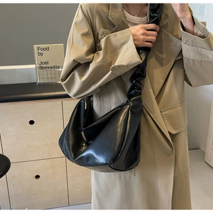Détail d'un grand sac cabas noir en cuir avec une bandoulière plissée de style scrunchie