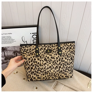 Detail of leopard print tote bag with black leather straps and gold stud accents