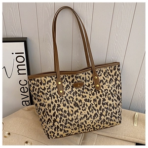 Detailed view of leopard print tote bag with brown leather handles and stitched logo