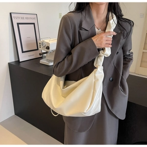 Détail du sac croissant blanc crème brillant avec bandoulière plissée unique