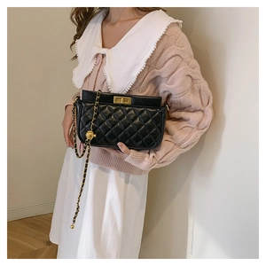 Detail of black quilted leather bag with gold twist lock and decorative metal ball
