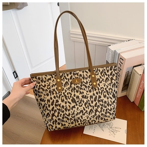 Detailed close-up of leopard print tote bag with brown leather handles and brand logo