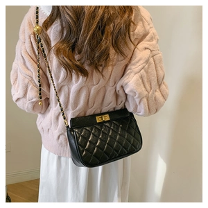 Detail showing black quilted chain bag with gold ball charm on model back view
