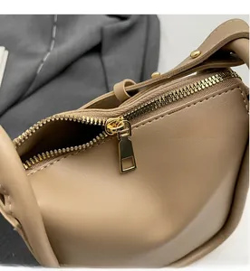 Detailed close-up of golden metal zipper and smooth stitching on a khaki bucket bag