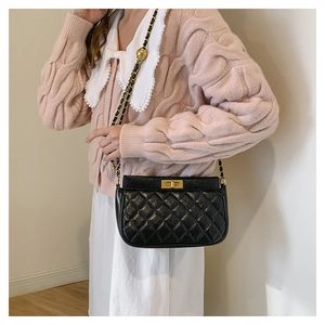 Detail of black quilted leather shoulder bag with gold twist lock and chain strap
