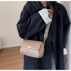 Detail of light brown lychee grain leather crossbody bag with geometric woven strap