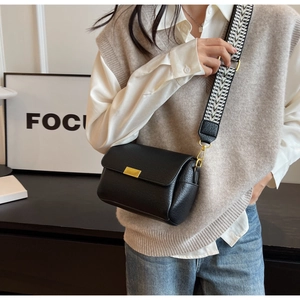 Détail du sac bandoulière en cuir noir avec fermoir doré et bandoulière géométrique