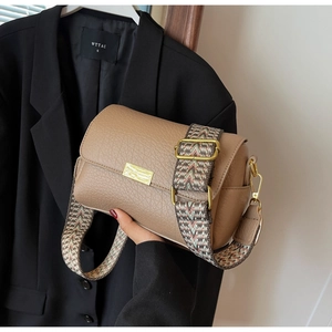 Detail of tan pebble leather crossbody bag with wide ethnic pattern strap and gold hardware