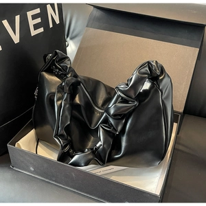 Gros plan d'un sac cabas plissé en cuir noir brillant dans un emballage de luxe