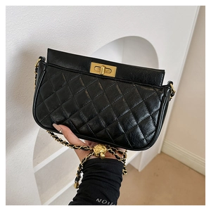 Close-up of black quilted leather shoulder bag featuring vintage gold twist-lock and chain