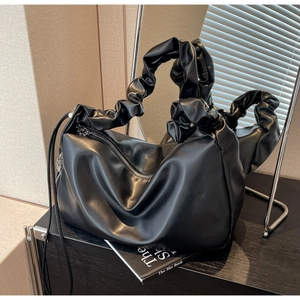 Gros plan du sac fourre-tout plissé noir avec poignée à volants sur une table en bois