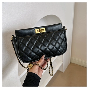 Macro detail of black quilted leather shoulder bag with vintage gold turn-lock and chain