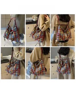 Detail of red leather strap and multi-color plaid fabric on versatile tote bag