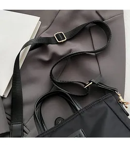 Close-up of black nylon bucket bag with adjustable wide strap and gold hardware