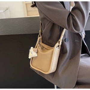 Detail of a khaki PU leather bucket bag with a cute plush bear charm and fashion text