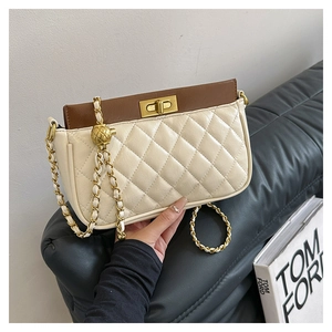 Detail of a quilted crossbody bag with gold tone turn-lock and adjustable metal ball chain