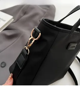 Close-up of durable golden metal hook and detachable strap on black nylon handbag