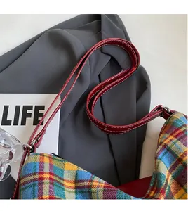 Detail of tartan canvas tote with red leather long strap and silver metal hardware