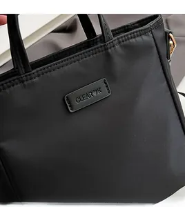 Close-up of CLEAROK brand logo patch and golden hardware on black nylon tote bag
