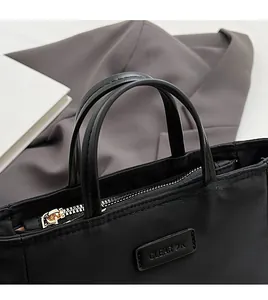 Detailed macro view of black nylon bucket bag with dual handles and metal zipper top
