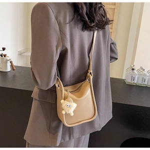 Detail of beige leather bucket bag with Fashion text and plush monster pendant charm