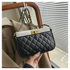 Detail of black and white quilted crossbody bag with gold twist lock and chain strap