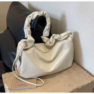 Détail du sac cabas plissé blanc crème avec fermetures éclair argentées sur pierre