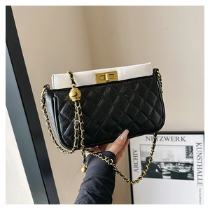 Detail of black quilted leather crossbody bag with white flap and adjustable gold ball chain