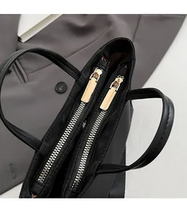 Close-up of durable golden double zippers on black tote bag with premium leather handles