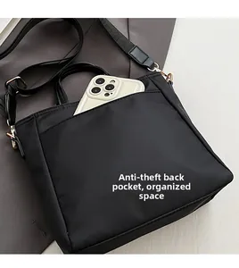 Detail of the back anti-theft pocket on the black nylon bag with a phone inserted