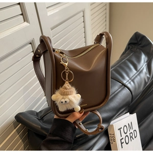 Detail view of brown PU leather bucket bag with gold zipper and star plush pendant accessory