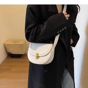 Detail of white saddle bag with golden metallic lock and fine stitching on faux leather