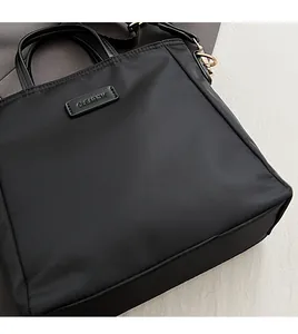 Detailed close-up of the black nylon tote bag featuring a leather CLEARBOOK brand patch