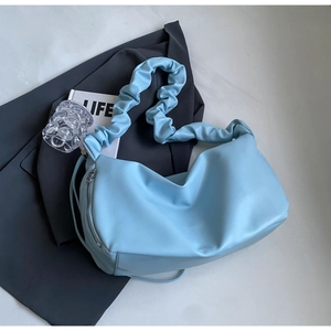 Détail du sac nuage bleu clair avec texture cuir souple et bandoulière plissée élégante