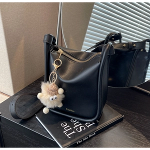 Detail of black matte bucket bag with golden Fashion logo and plush monster charm