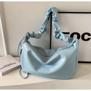 Gros plan sur la bandoulière plissée bleu clair et la texture du cuir PU du sac hobo