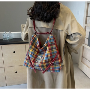 Close-up of tartan plaid tote bag with red leather trim and silver NYR logo emblem