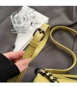 Detail of yellow crocodile texture shoulder strap with adjustable dark grey metal buckle