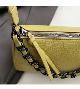 Detail of smooth black metal zipper and textured lime leather strap on luxury crossbody bag