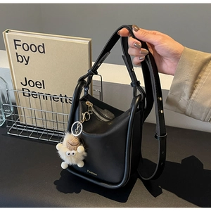 Close-up of black matte bucket bag with a cute sheep keychain and fashion gold lettering