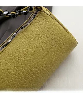 Close-up of mustard green leather texture with black metal chain and zipper detail