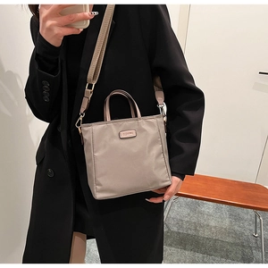 Detail of taupe nylon crossbody bag with wide shoulder strap and clearun metal logo