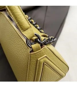 Detail of lime yellow leather bag with V-shaped stitching and gunmetal chain link hardware
