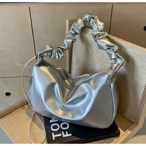 Détail du sac cabas argenté métallisé avec poignée froncée et ruban rose sur support bois