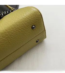 Close-up of olive green litchi grain leather bag with protective metal bottom studs